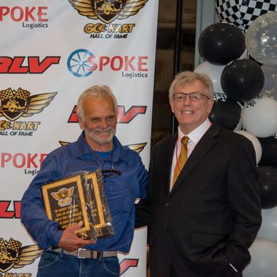 Two men posing at a go-kart hall of fame event.