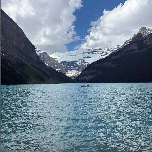 Boat on a blue lake surrounded by mountains.
