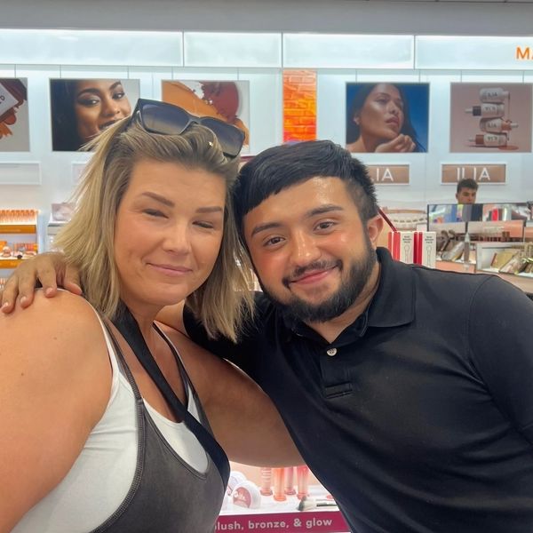 Two people smiling inside a makeup store.