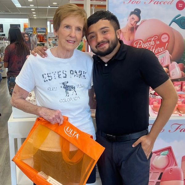 Two people smiling in a store with an orange Ulta bag.
