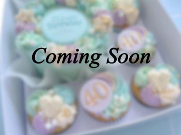 Blurred image of decorated cupcakes with 'Coming Soon' text.