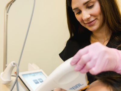 Professional woman performing a laser facial treatment.