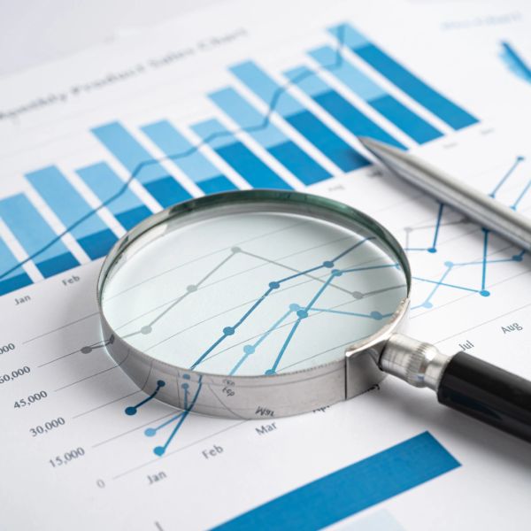 Magnifying glass over financial charts with a pen.