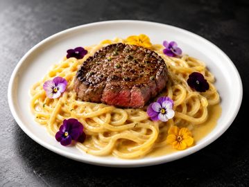 Plato de pasta con filete y flores comestibles.