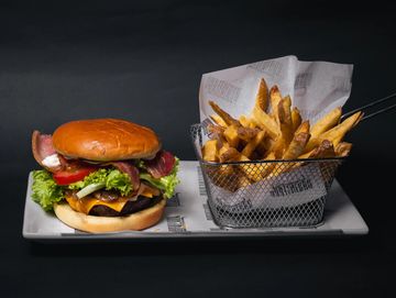 A cheeseburger with bacon and fries on a white plate.