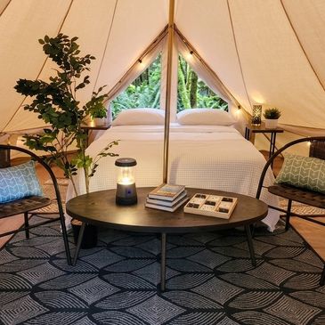 Cozy glamping tent interior with a bed and seating area.