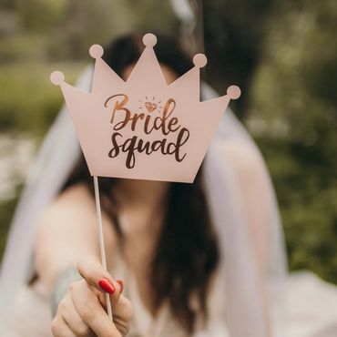 Woman holding a "Bride squad" crown sign, celebrating a wedding event.