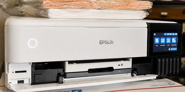 Epson printer with touchscreen and papers on top.