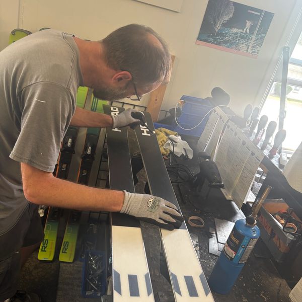 Man tuning skis on a workbench.