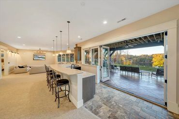 Spacious open living area with bar seating and large patio doors opening to outdoor lounge.