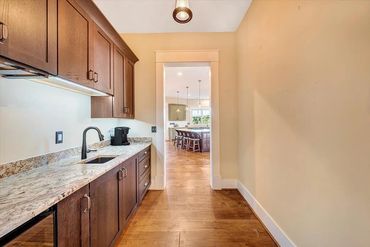 Long pantry with dark wood cabinets and granite countertop.