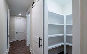 Empty white pantry shelves in a modern home hallway.