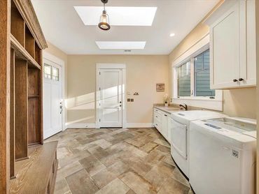 Bright laundry room with washer, dryer, and wooden storage bench.