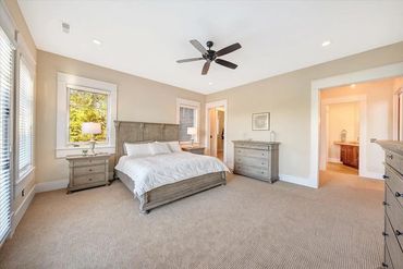Spacious bedroom with beige walls, carpet flooring, and wooden furniture.