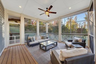 Cozy screened-in porch with wicker furniture and nature views.