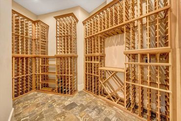 Empty wooden wine racks in a spacious cellar with tiled flooring.