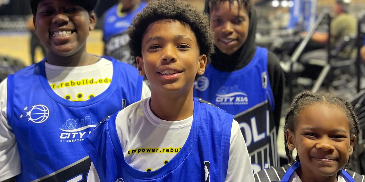 Group of smiling kids in blue basketball jerseys.
