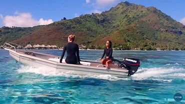 Two female scientists motor a boat across tropical waters in Mo'orea, French Polynesia.