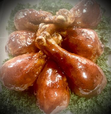 Glazed chicken drumsticks arranged on a bed of leafy greens.