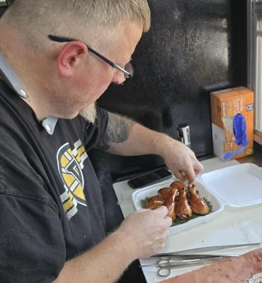 Man arranging cooked chicken drumsticks in a white container.
