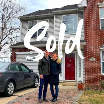 Happy couple standing in front of their newly sold house.