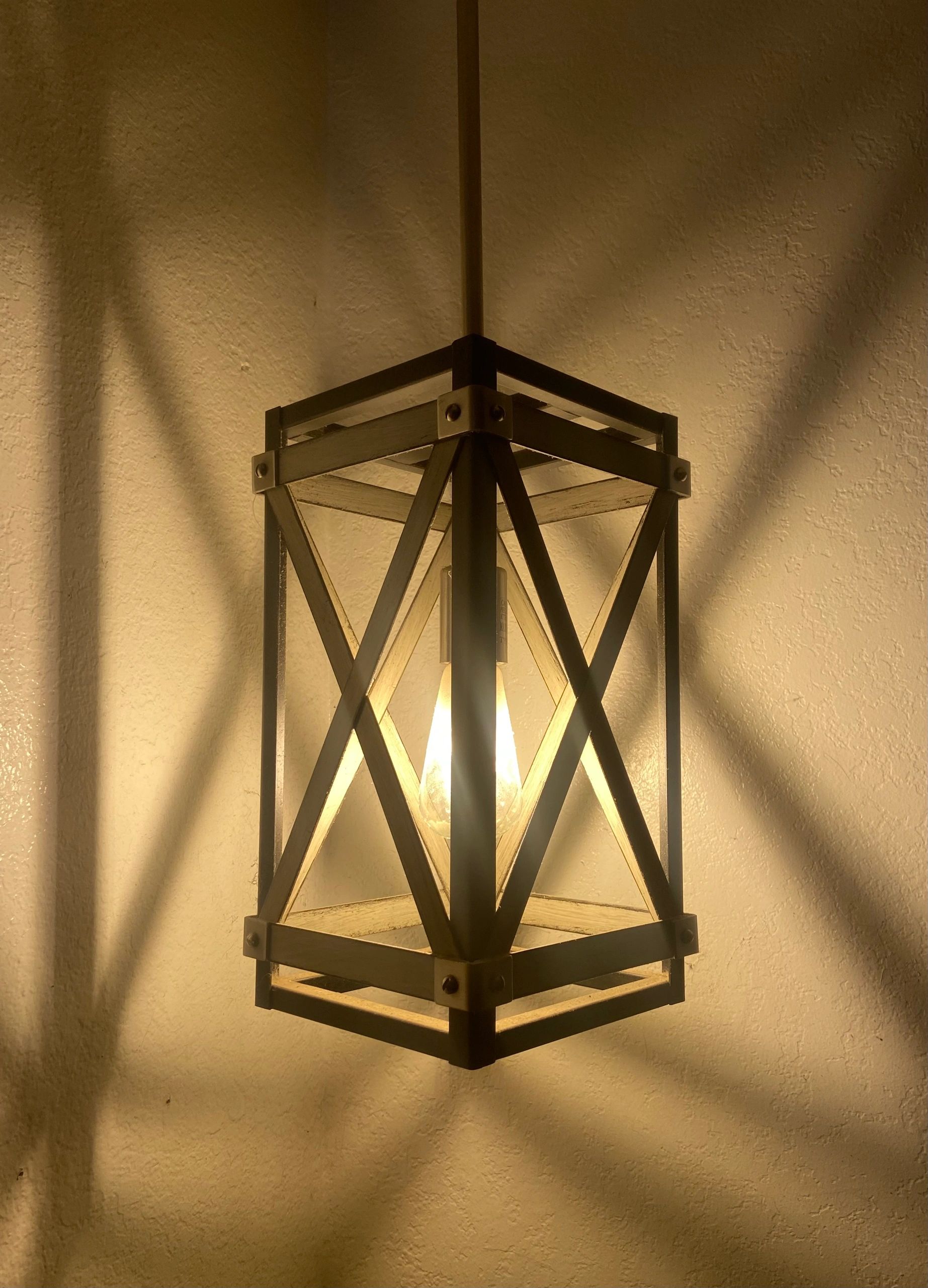 A glowing lantern casting intricate shadows on a textured wall.