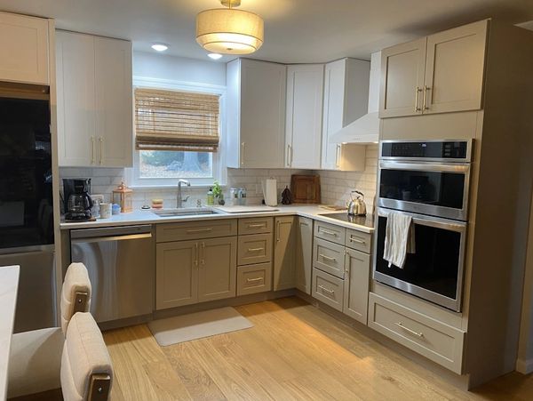 Modern kitchen with beige cabinets, stainless steel appliances, and wooden floor.