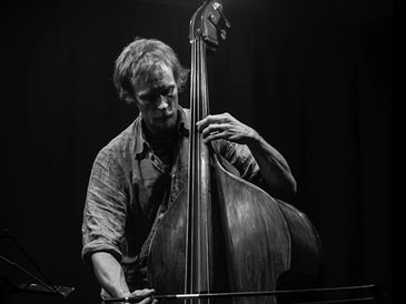 man playing double bass against a black background