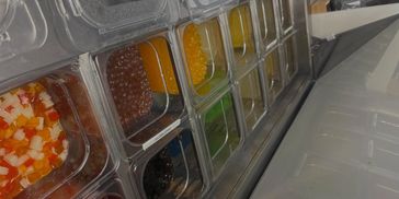 Various colorful bubble tea toppings in transparent containers.
