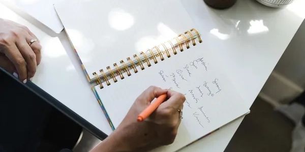 a person writing in a notebook, shows their hands only