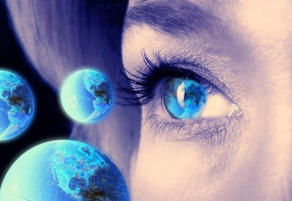 Close-up of a blue eye with floating blue spheres around it.