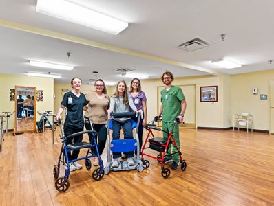 Five healthcare workers with walkers standing in a clinic room.