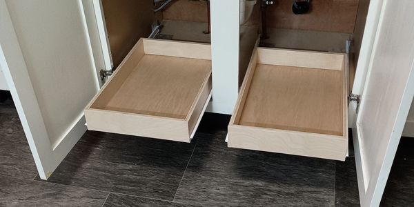Two wooden pull-out drawers inside kitchen cabinets.