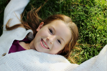 Little girl laying in grass outdoors in summer. Missoula, Montana photographer. 