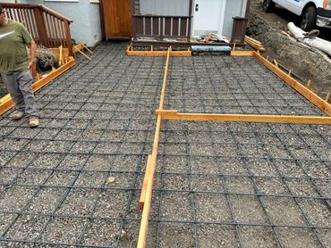 Construction site with rebar grid and wooden framing for concrete slab.