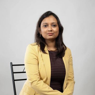 Professional woman in yellow blazer seated.
