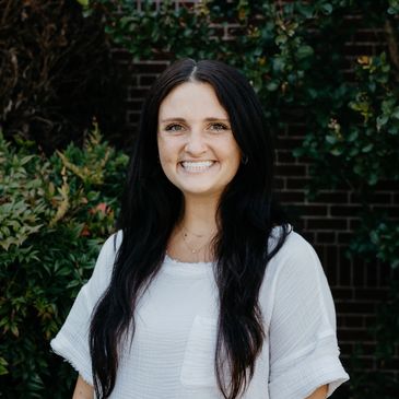Smiling woman with long dark hair outdoors.