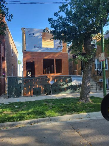 A residential building under construction with Tyvek wrap and wooden framing.