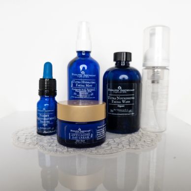 Blue skincare bottles and jars arranged on a clear decorative mat.