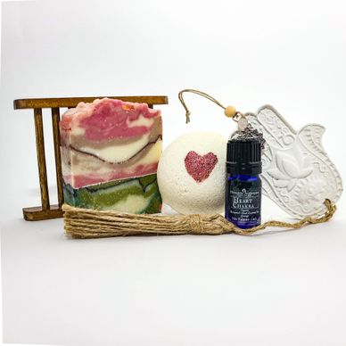A colorful soap bar, bath bomb with heart, essential oil, and decorative items.
