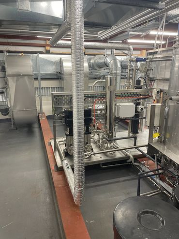 Industrial mechanical room with insulated pipes and pumps.