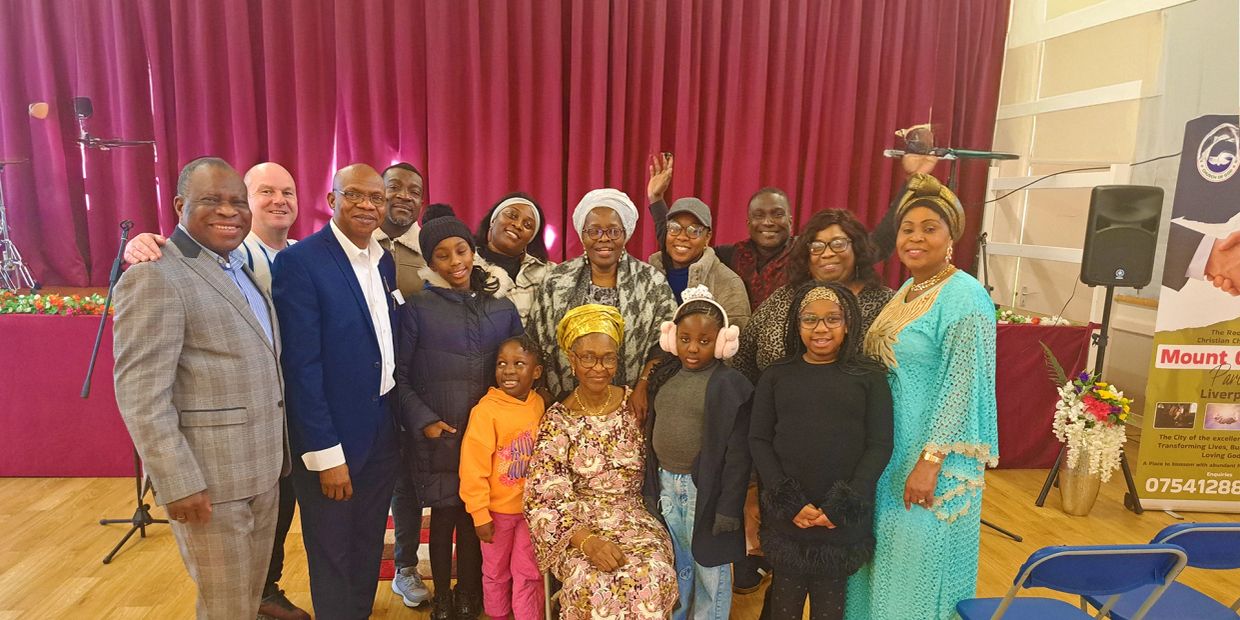 Family group photo in a hall with red curtains.