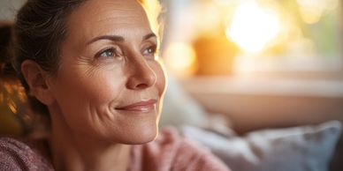 A woman gazes peacefully into the sunlight with a gentle smile.