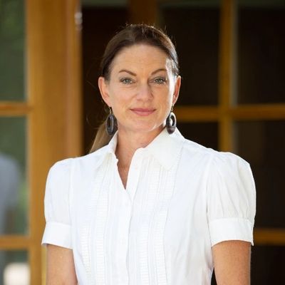 Confident woman in a white blouse with earrings, standing indoors.