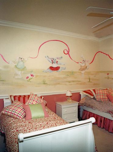 A wall painting of three bunnies playing with a ribbon