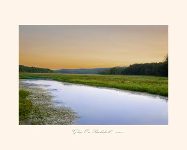 Tranquil river winding through green fields at sunset.