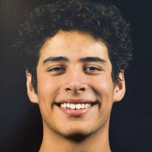 Young man with curly hair smiling.