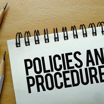 Notepad with 'Policies and Procedures' text and three pencils on a wooden surface.