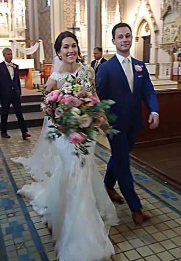 This is an image of the bride and groom walking up the aisle. The bride is smiling big at the camera