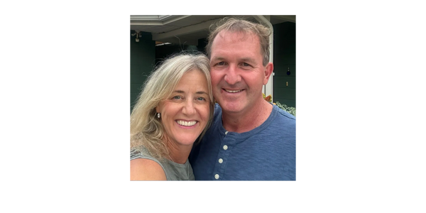 Smiling couple posing for a close-up selfie outdoors.